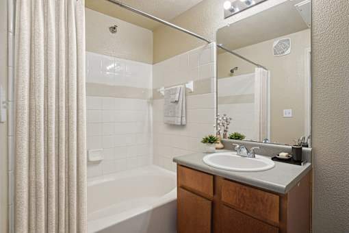 A bathroom with a white tub, sink, and a mirror.