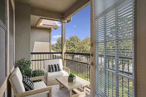 A patio with a white chair and a small table with a plant on it.