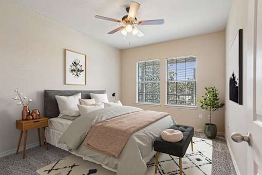 A bedroom with a bed, a chair, and a ceiling fan.