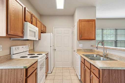 A kitchen with white appliances and wooden cabinets.