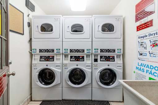 Hayward, CA Apartments - Paseo Gardens - Onsite Laundry Room with Stacked White Machines