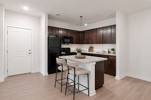 A kitchen with a black refrigerator and brown cabinets.