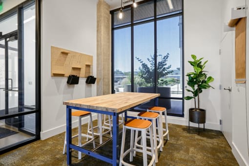 a dining area with a wooden table and four stools in front of a window