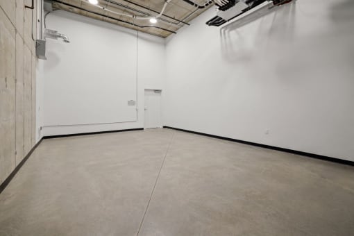 an empty room with a white wall and a cement floor
