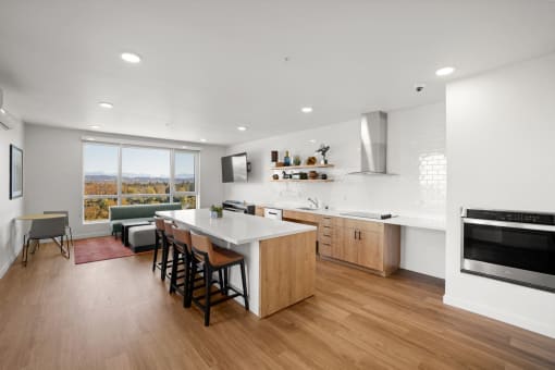 a kitchen and living room with a white counter top and wood floors
