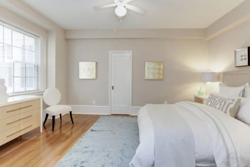 A bedroom with a bed, a chair, and a ceiling fan.