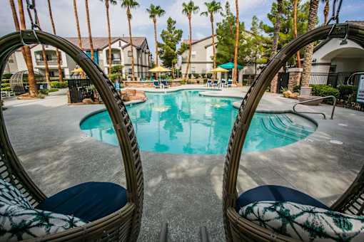 A swimming pool surrounded by palm trees and apartment buildings.
