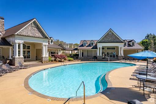 A swimming pool surrounded by lounge chairs and umbrellas.