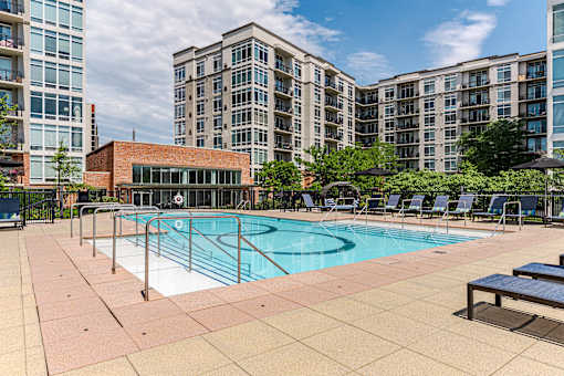 A swimming pool surrounded by lounge chairs and a building in the background.