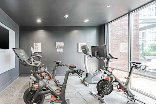 A row of exercise bikes are lined up in a room.