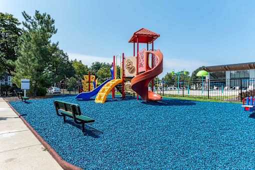 A playground with a blue rubber surface and a red and yellow slide.