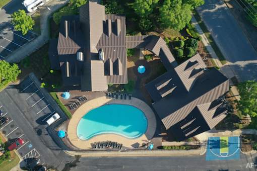 An aerial view of a building with a pool and a basketball court.