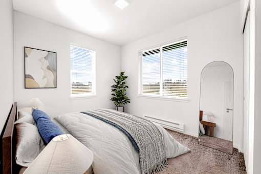 A bedroom with a large bed and a small tree in the corner.