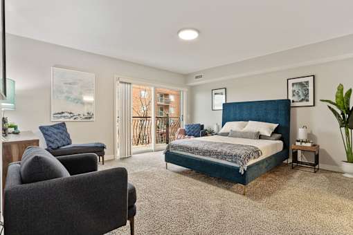 A bedroom with a large bed and a chair.