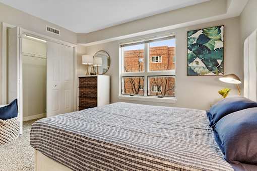 A bedroom with a large bed and a window overlooking a brick building.