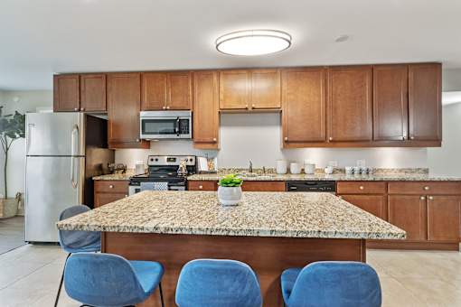 A kitchen with a granite countertop and blue chairs.