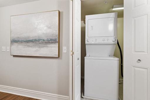 A white fridge in a room with a painting on the wall.