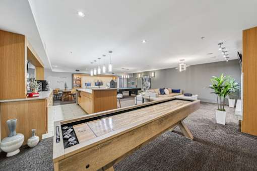 A shiny wooden table is in the middle of a carpeted room with a bowling alley.