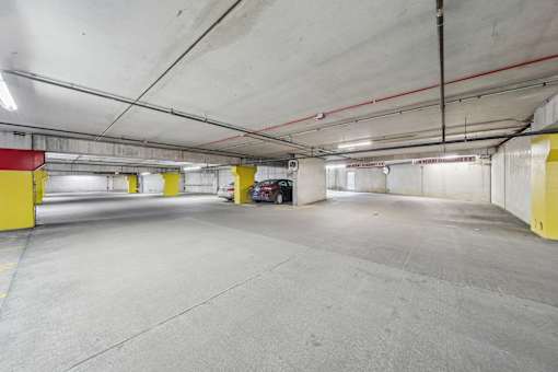 A spacious parking garage with concrete floors and yellow safety barriers.