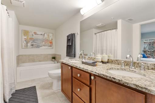 Spacious apartment bathroom with granite vanity, wood cabinetry and soaking tub