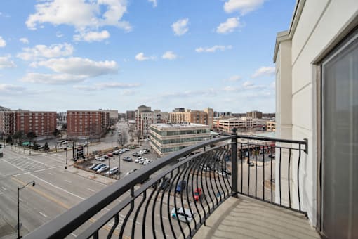 A balcony overlooks a city street with cars and buildings.