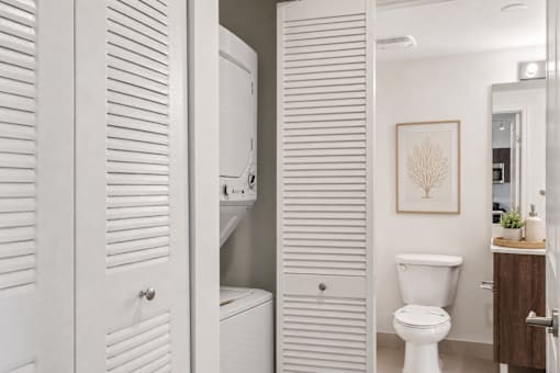 A white toilet sits in a bathroom next to a white cabinet.