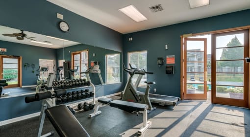 Two Bedroom Apartments in Coeur d’Alene ID - Rockwood Lodge - Fitness Center with Exercise Equipment, Weights, a Large Window, and a Door with Pool Access
