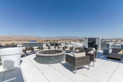 a fire pit and lounge area on the roof of a building with mountains in the background