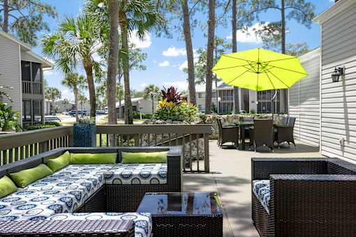 A patio with a yellow umbrella and a blue and white couch.