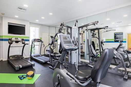 A gym with a variety of equipment including treadmills, stationary bikes, and weight machines.