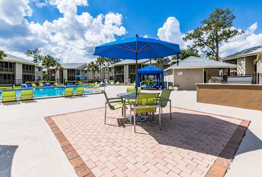 A patio with a table and chairs under a blue umbrella.