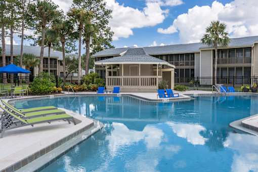 A swimming pool with a sun lounger and a building in the background.