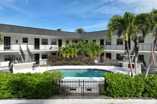 a large pool in front of a hotel with palm trees