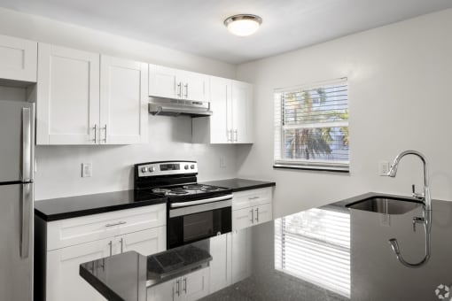 a kitchen with white cabinets and black counter tops