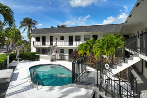 a house with a swimming pool and a building with palm trees