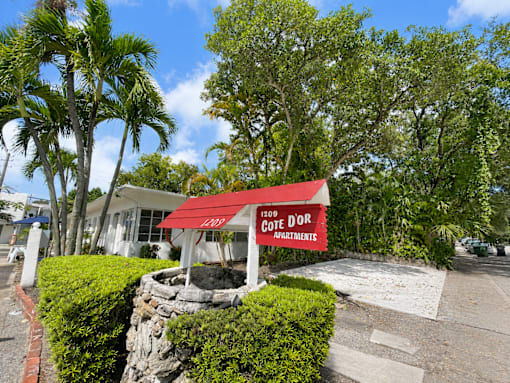A red sign with white lettering on a building reads "1209 Gotee Dr Apartments".