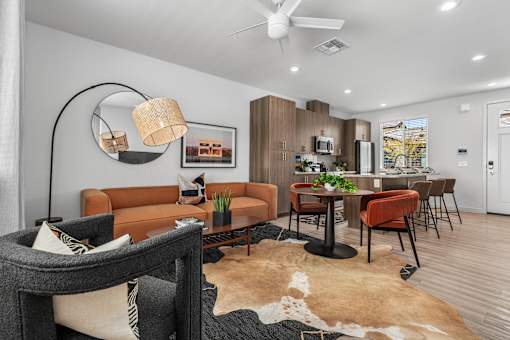 A living room with a brown leather couch and a black and white cowhide rug.