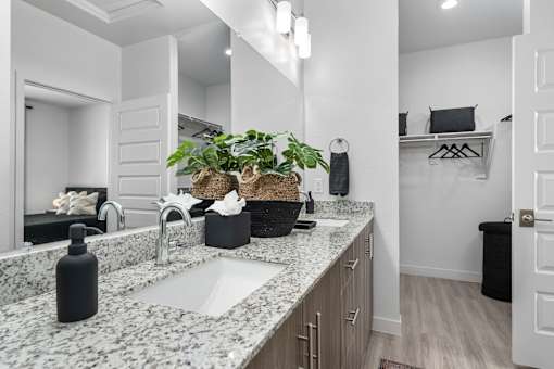 A bathroom with a marble countertop and a large mirror.