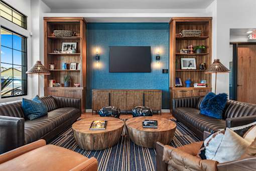 A living room with a brown leather couch, a wooden coffee table, and a flat screen TV mounted on the wall.