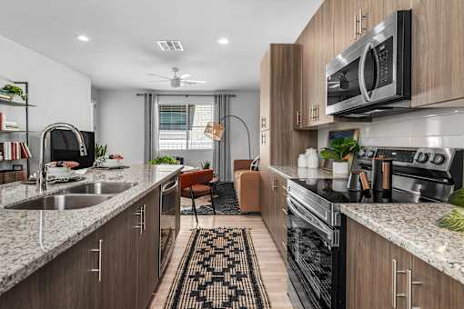A modern kitchen with a sink, stove, and microwave.