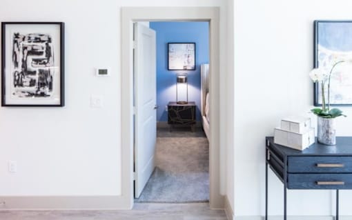 A black and white picture hangs on a white wall above a white door.