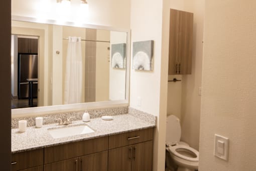 A bathroom with a sink, mirror, toilet and a cabinet.