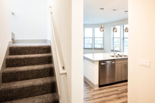 A staircase leads to a kitchen area with a sink and cabinets.