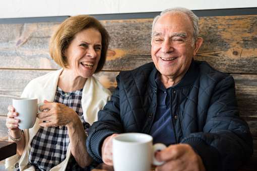 Happy senior couple relaxing with coffee at Sage 5430 pet-friendly 55+ apartments in Norcross, GA