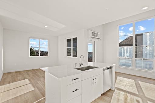A modern kitchen with white cabinets and a large window.