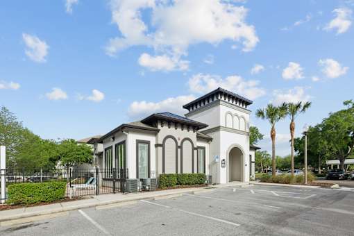 A small white building with a black roof and a black fence in front of it.