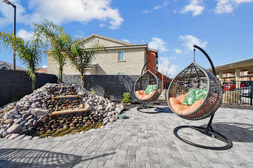 A patio with two hanging chairs and a fire pit.