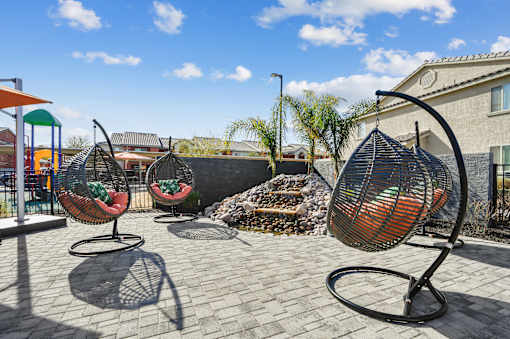 Four hanging chairs are placed on a patio.