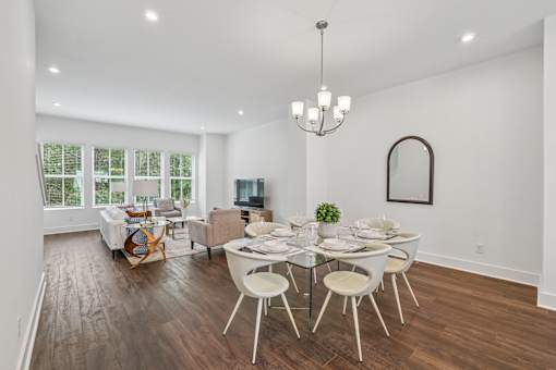 A dining room with a glass table and white chairs.