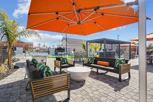 A patio with a table, chairs and an orange umbrella.